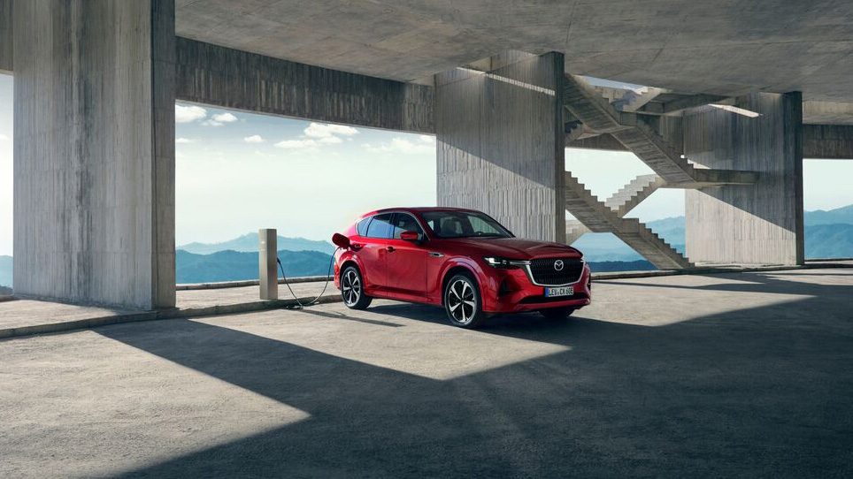 De vernieuwde Mazda CX-60 in de kleur Soul Red Crystal aan een laadpaal.